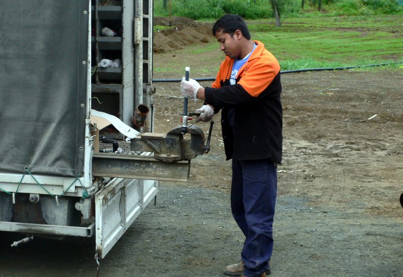 Young professional plumber in grey uniform using equipment on th